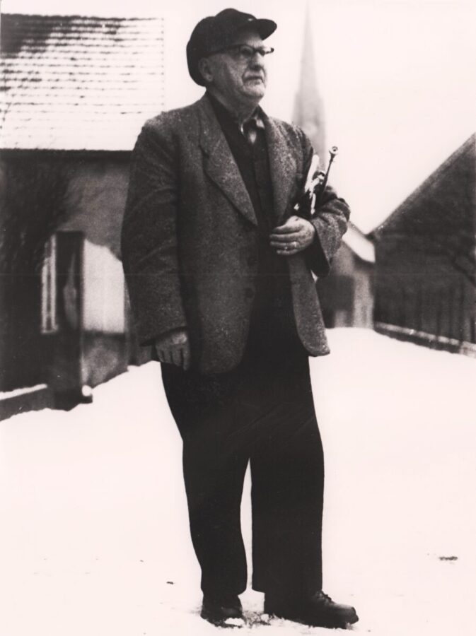 Wandermusikant "Ottopatt" Otto Rheinheimer mit seiner Trompete im Schnee, im Hibnergrund die Protestantische Kirche | Aufnahme nach 1845